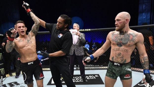 Dustin Poirier's hand is held aloft after beating Conor McGregor at UFC 257