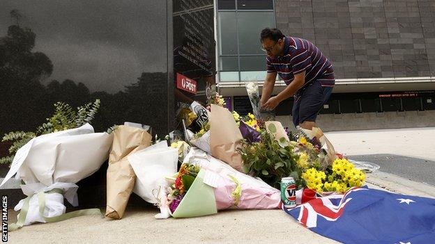 A man lays flowers at Shane Warne's statue at the Melbourne Cricket Ground