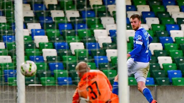 Sam Roscoe watches his header beat Aaron McCarey and go into the Glentoran net