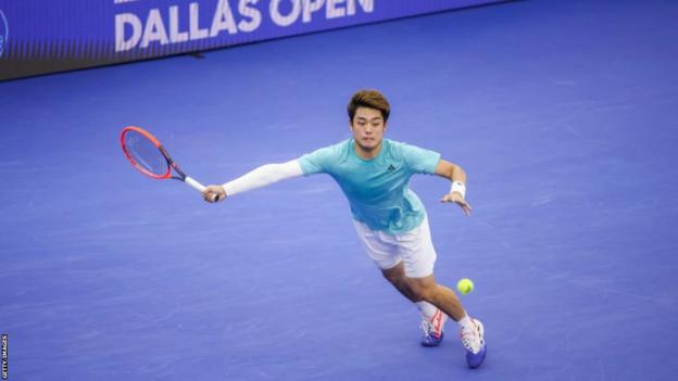 Wu Yibing stretches to his right to hit a forehand return