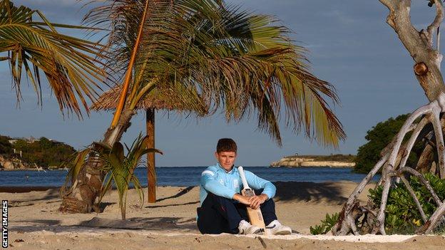 Jacob Bethell sits on the beach