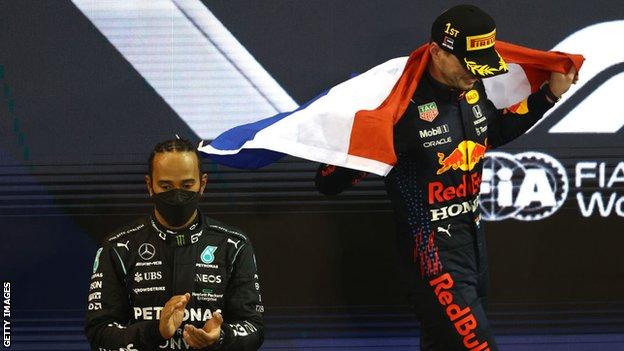Maxas Verstappenas švenčia, kai Lewisas Hamiltonas ant podiumo Abu Dabyje atrodo prislėgtas
