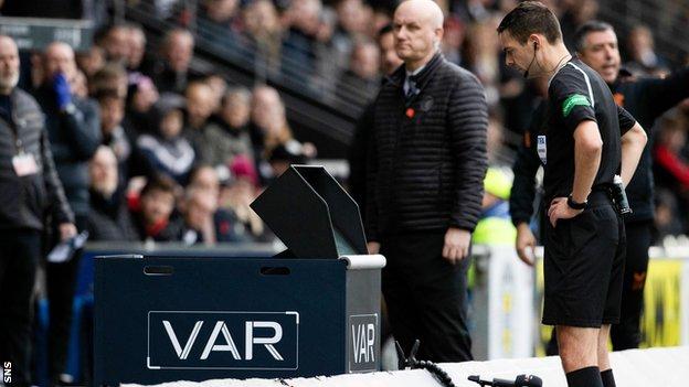 Referee Kevin Clancy reviews a penalty incident on VAR