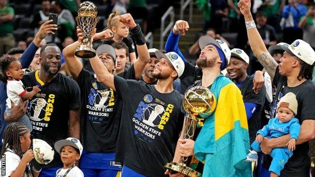 Teammates Stephen Curry and Golden State Warriors with their trophies after winning the NBA title in 2022.