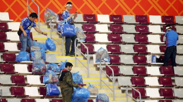 Japan fans clean the stadium