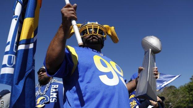 A Los Angeles Rams fan holding a flag during the team's trophy parade