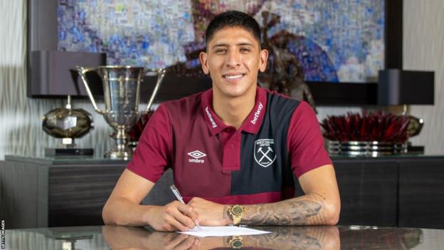 Edson Alvarez sits at a desk as he signs for West Ham