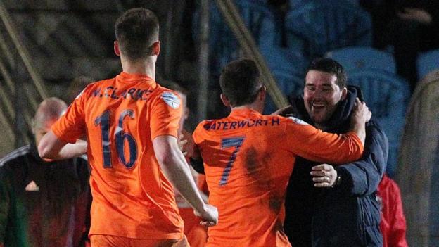 Matthew Clarke and Andrew Waterworth run to celebrate with Linfield manager David Healy as Linfield take the lead against Ballymena