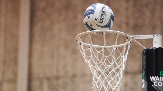 A netball falls into a hoop