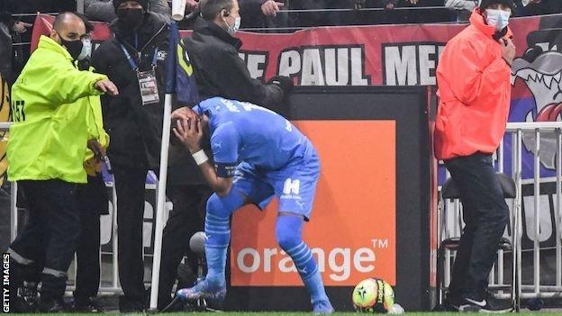 Dimitri Payet holds her head after being hit by a bottle