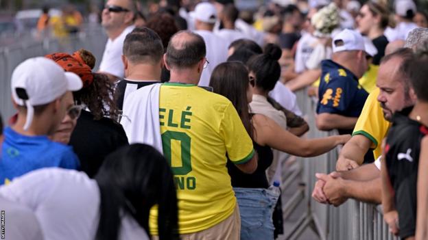 Fans queue outside the Urbano Caldeira Stadium ahead of football legend Pele's funeral