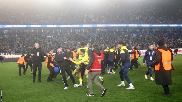 Players and fans clash on the pitch after the game between Trabzonspor and Fenerbahce
