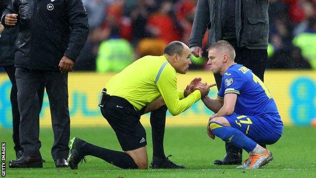 Referee Antonio Mateu Lahoz consoles Oleksandr Zinchenko