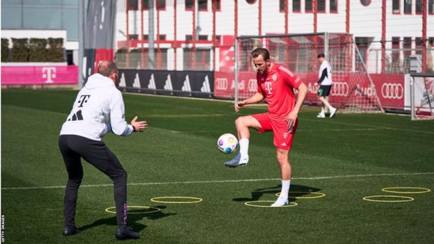 Harry Kane passes the ball to a coach in training
