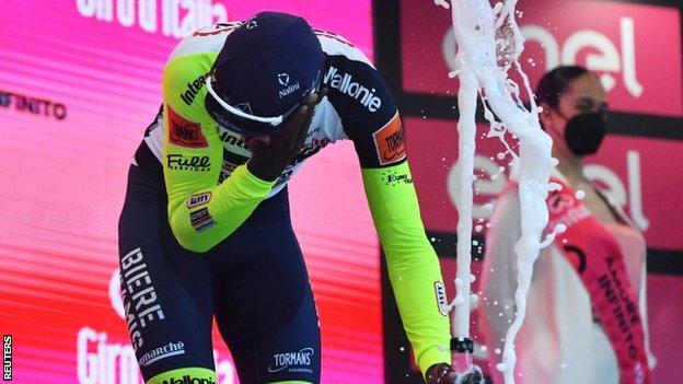 Biniam Girmay injures his eye with the prosecco cork on the podium after winning stage 10 of the 2022 Giro d'Italia