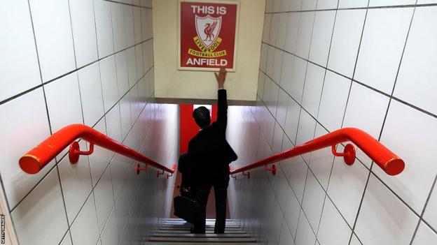 John Henry touches the This is Anfield sign during a stadium tour in 2010