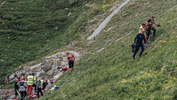 Gino Mader receives medical attention after crashing during the fifth stage of the Tour de Suisse, while Magnus Sheffield from the USA of Ineos Grenadiers is being assisted by medical staff and walks away.