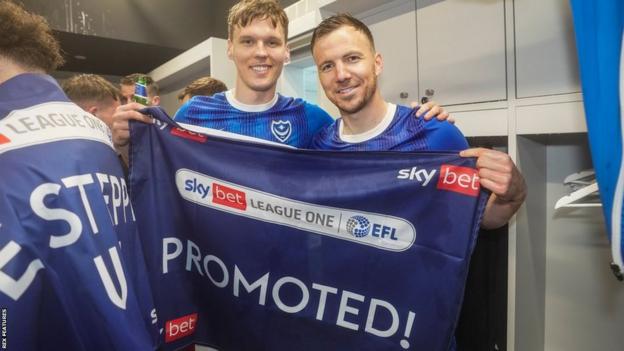 Sean Raggett (left) and Lee Evans (right) hold a promotion flag