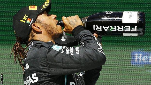 Lewis Hamilton bebe champanhe no pódio