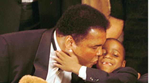 Muhammad Ali holds a UCP bear and kisses Yasin Shelton, a cerebal palsy patien