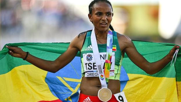 Gudaf Tsegay wears a gold medal and carries Ethiopian flag