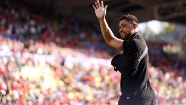 Taulupe Faletau waves to Wales fans with his arm in a sling