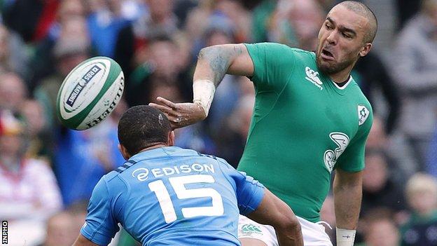 Simon Zebo produces an off-load as he is tackled by Italy full-back David Odiete