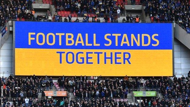 'FOOTBALL STANDS TOGETHER' displayed on big screen