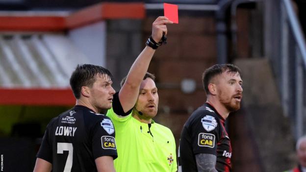 Referee Christopher Morrison dismisses BJ Burns (right) in the first half of the Seaview encounter