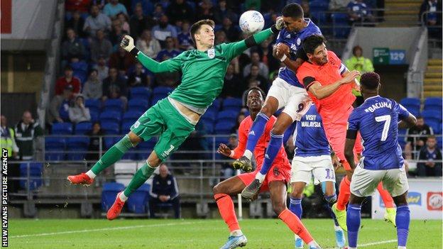 Cardiff City's Robert Glatzel heads towards goal under the challenge of Huddersfield Town goalkeeper Kamil Grabara