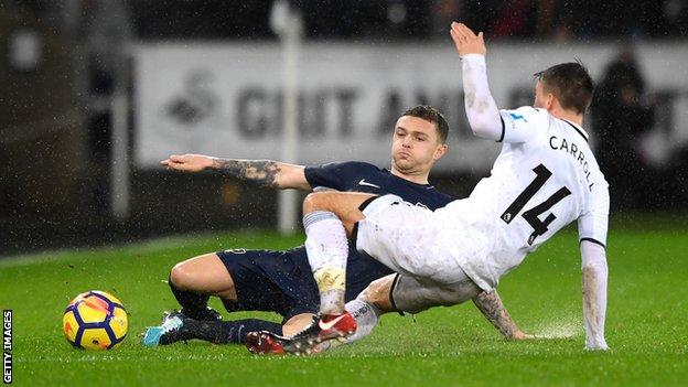 Kieran Trippier of Tottenham Hotspur is challenged by Swansea City's Tom Carroll on the rain-drenched Liberty Stadium pitch