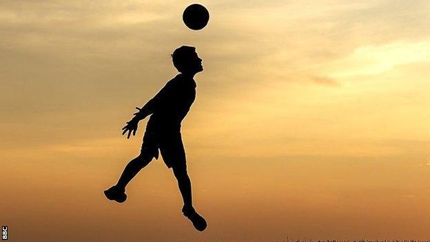 A boy heading a soccer ball