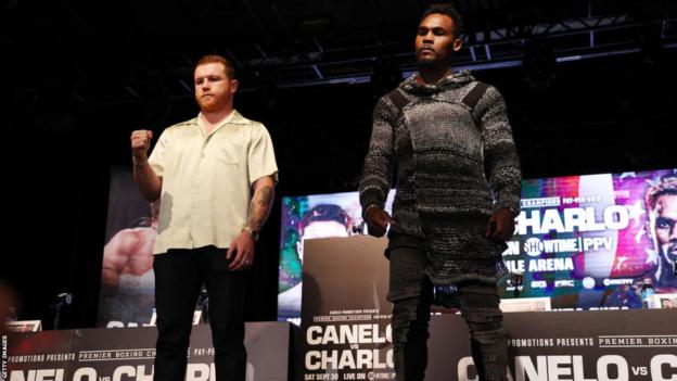 Saul 'Canelo' Alvarez raises a fist as he stands beside Jermell Charlo while they pose for pictures