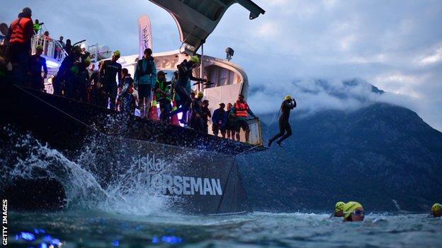 Triathletes jump off the back of a car ferry to start the Norseman Xtreme Triathlon