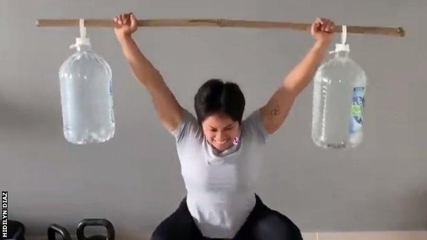 Hidilyn Diaz, bambu çubuklardan ve su şişelerinden yapılmış derme çatma ağırlıkları kaldırıyor.