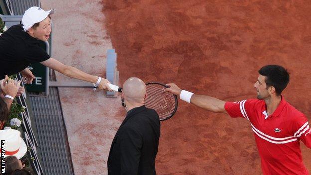 Novak Djokovic gives his racquet to a young fan