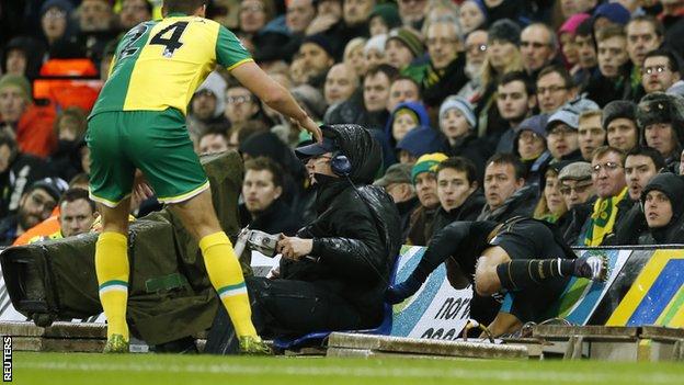 Alexis Sanchez (right) falls into the barriers at Norwich