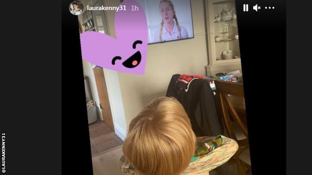 The back of a child's head, with the child watching Laura Kenny on television