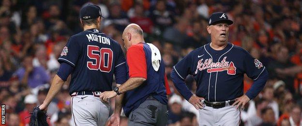 Atlanta Braves pitcher Charlie Morton is helped off the field as manager Brian Snitker looks on