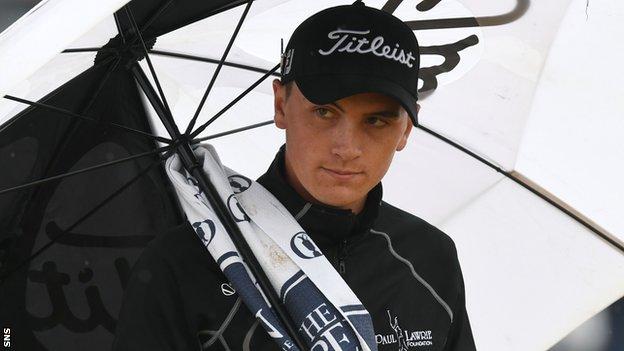 Young Scottish amateur Sam Locke shelters from the rain at a wet Carnoustie