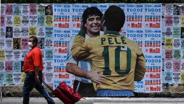 Street poster art by Luis Bueno, depicting Brazilian football legend Pele hugging Argentinian football legend Diego Maradona in Sao Paulo, Brazil
