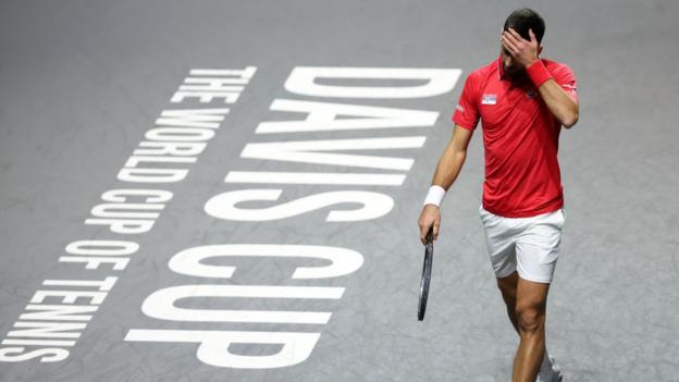 Novak Djokovic face palms his forehead in frustration on court at the Davis Cup