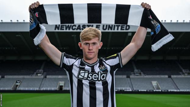 Lewis Hall poses for photos wearing a shirt and scarf in St. James' Park