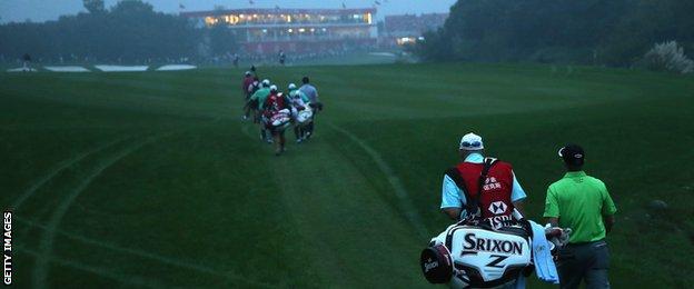Russell Knox walks down the 18th fairway in the fading light