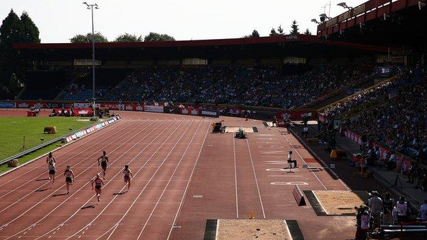 Athletes running on a track in front of a crowd