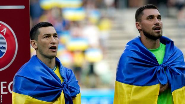 Ukraine's players draped themselves in their country's flag as they took to the field to sing their national anthem