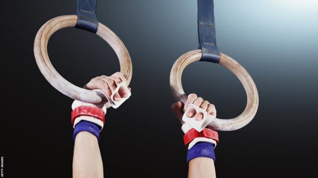 Young gymnast hanging from rings