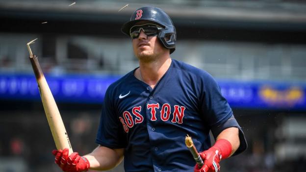 Hunter Renfroe, wearing a blue Boston Red Sox jersey, breaks a baseball hat over his head in frustration
