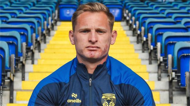 Brad Dwyer sat on the steps at the Halliwell Jones Stadium after re-signing for Warrington