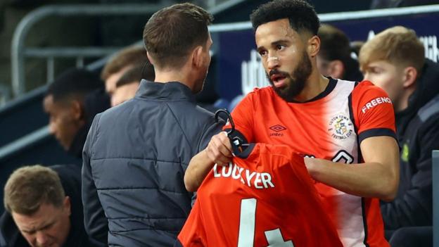 Luton Town's Andros Townsend celebrates scoring their first goal and holds a shirt to support of Luton Town's Tom Lockyer who is recovering following a cardiac arrest